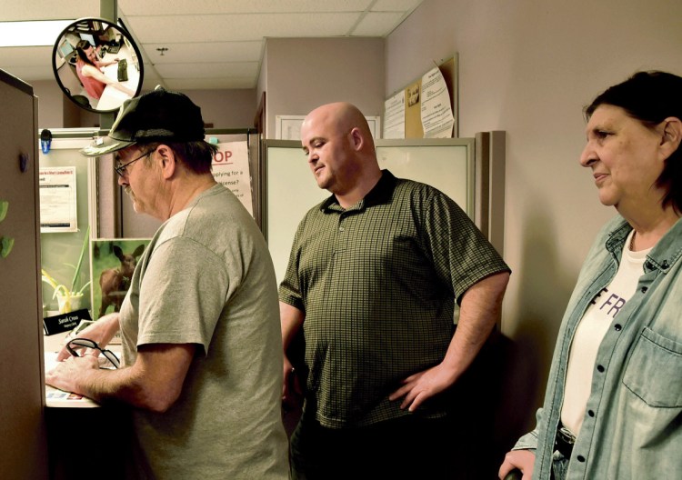 Patrick Roy, left, speaks with Waterville Deputy Clerk Sarah Cross, seen in mirror, at City Hall while filling out paperwork for a petition to recall Ward 7 Councilor Jackie DuPont on May 7. Also participating in the recall effort is Roy's son Andy and wife Marilyn.