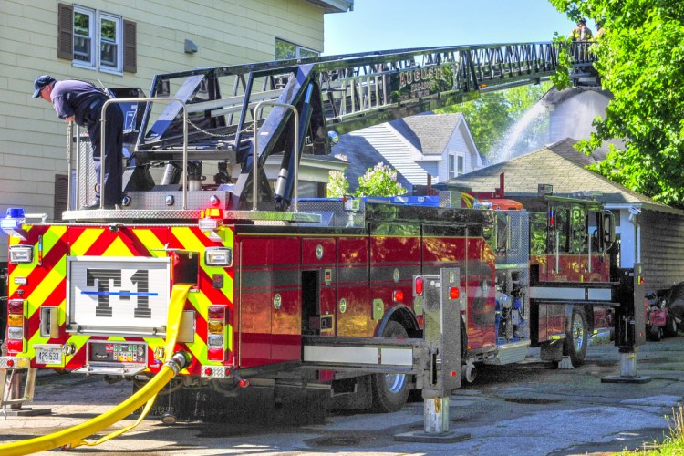 Firefighters on Augusta tower truck 1, parked on Myrtle Street, spray water onto the backside of 79 Willow St. in Augusta on Wednesday.