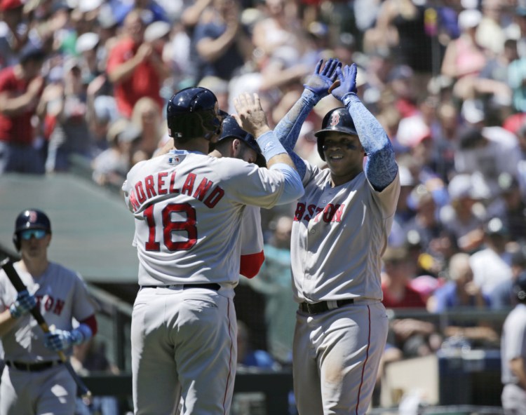 Boston's Rafael Devers, right, is greeted by J.D. Martinez, center, and Mitch Moreland, 18, after hitting a three-run home run during the Red Sox' 9-3 win over Seattle on Sunday in Seattle.