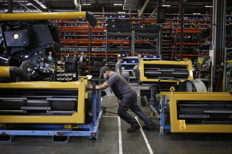 A worker assembles a combine harvester at the CLAAS of America Inc. production facility in Omaha, Neb., earlier this month. At least one Nebraska city, North Platte, will pay people to relocate.