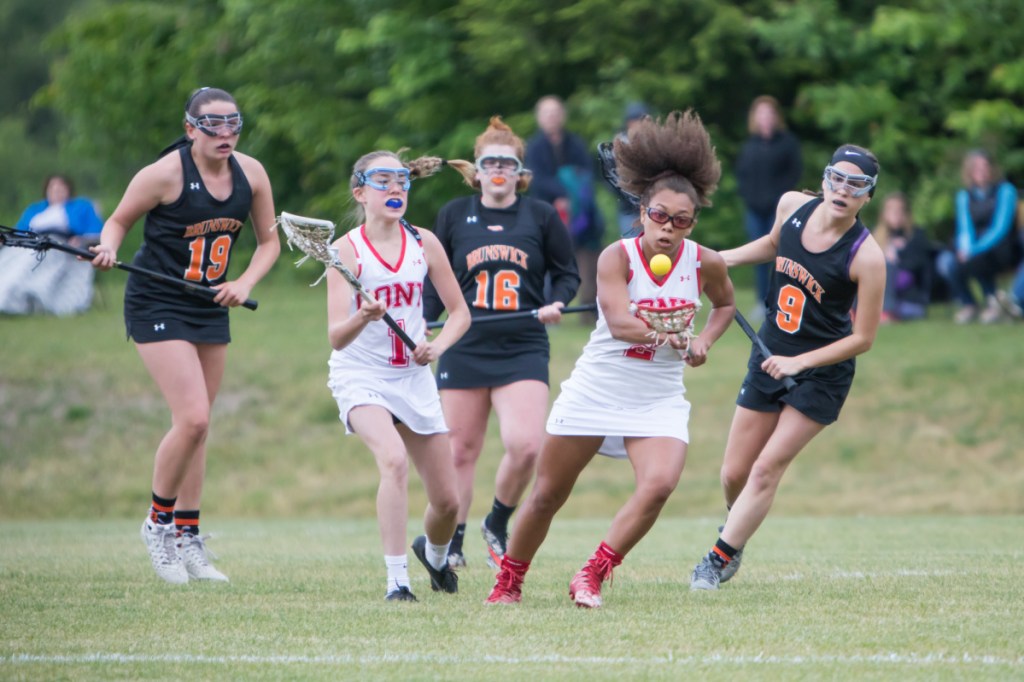 Cony's Kami Lambert carries the ball as Brunswick defenders Amanda Cloutier, Robyn Dumont, Tessa Alexander give chase during a Class B  lacrosse prelim Wednesday at Cony High School.