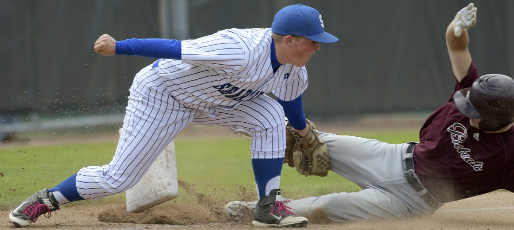 Richmond's Trystin Shea, right, knocks the third base out of the ground while sliding under Searsport's Connor Kneeland tag at home during a Class D South regional final game last week in Standish.