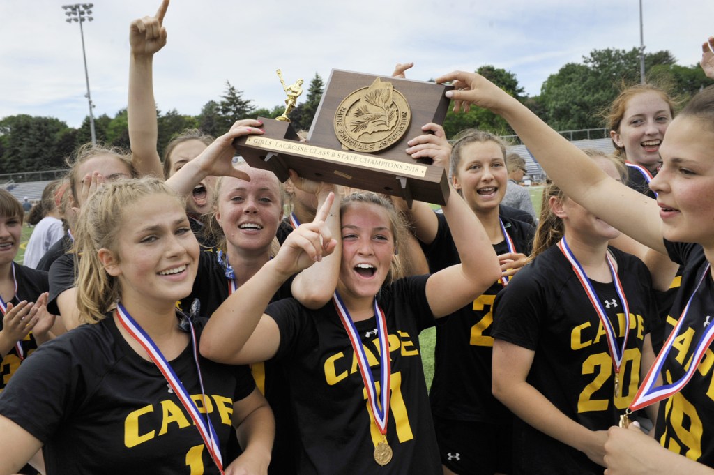 Cape Elizabeth's Cloe Chapin holds the Class B state championship plaque and celebrates with teammates after they won the state title Saturday in Portland.