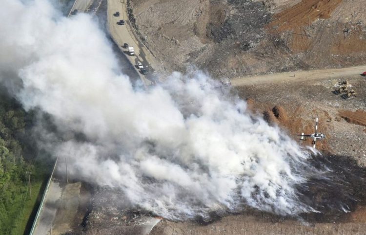 A Maine Forest Service helicopter finishes a pass after dropping water Tuesday on a smoky fire burning at the Waste Management Crossroads Landfill in Norridgewock.