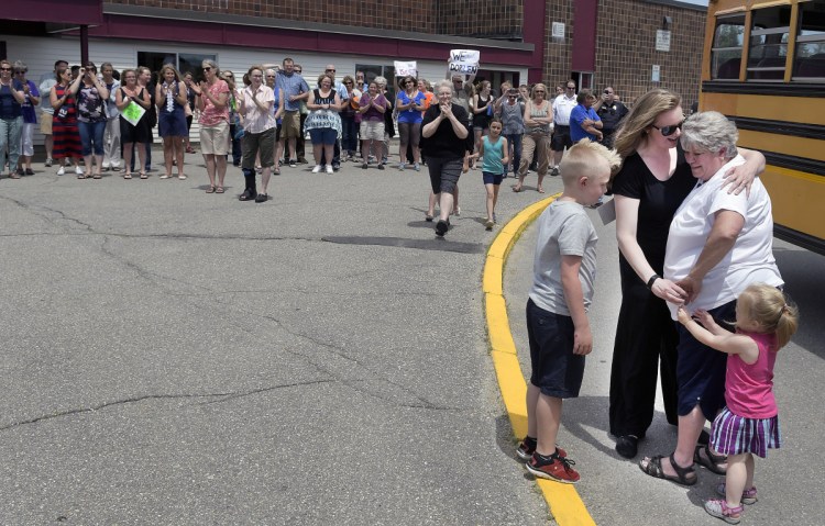 Students, friends, family and the faculty of the Richmond schools greet Doreen Moody, right, after she finished the last run of her career Wednesday as a bus driver in Richmond. The town's Police and Fire departments escorted Moody to the school, where she was greeted at the entrance by all of the community's teachers to conclude 31 years of delivering children safely.