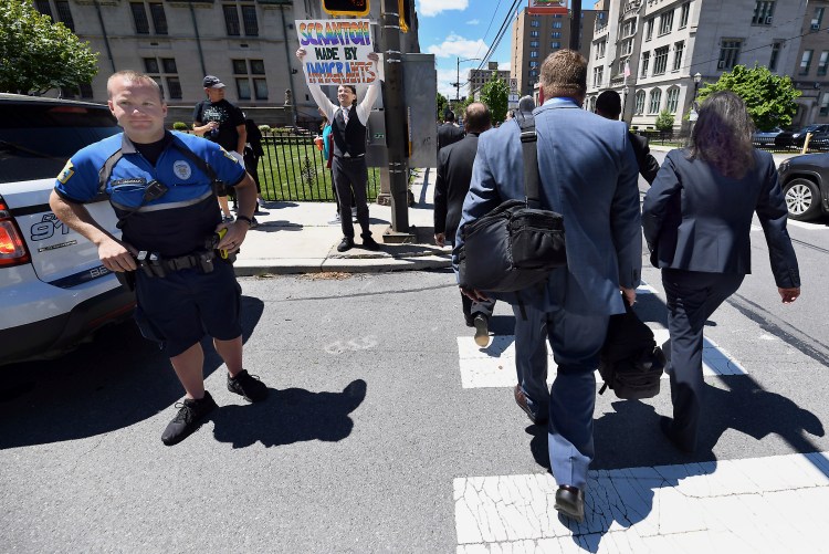 Jonathan Wilson, 33, of Scranton, Pa., holds a sign outside of a Lackawanna College were U.S. Attorney Jeff Sessions spoke on immigration policy and law enforcement actions, Friday in Scranton, Pa. Attendees who took part in listening to the speech cross the street at right.