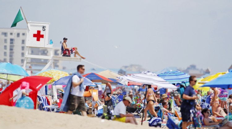 Matt Moriarty, 18, of Boston and Ocean Park, scans a busy crowd at noontime on a hot, humid Sunday at Old Orchard Beach. Moriarty, who is spending his first summer as a lifeguard here, says there are about 15 lifeguards working the beach this summer.