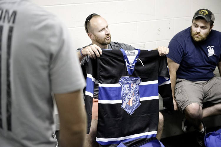 Lewiston police Officers Charlie Weaver, left, and Tyler Michaud look at the new hockey jerseys that the Lewiston Police Department hockey team wore during the game.