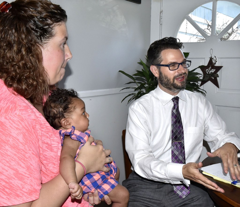 Mindy Saint Martin holds her two-month-old daughter Mya as attorney Evan Fisher talks about the upcoming hearing before a pardon board that will recommend to the governer whether or not to pardon her husband Lexius for a drug trafficking charge, which the family hopes will lead to his return to Waterville.
