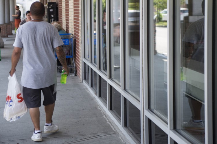 Greg Oullette carries groceries in a plastic bag Wednesday after shopping at Save-A-Lot in Waterville.