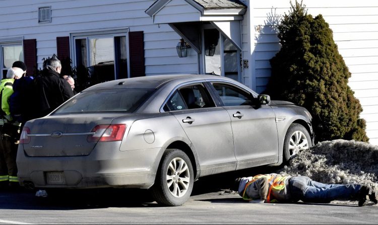 A tow truck operator looks under a vehicle that struck 50 Halifax St. in Winslow after the driver reportedly fell asleep while driving on Jan. 31.