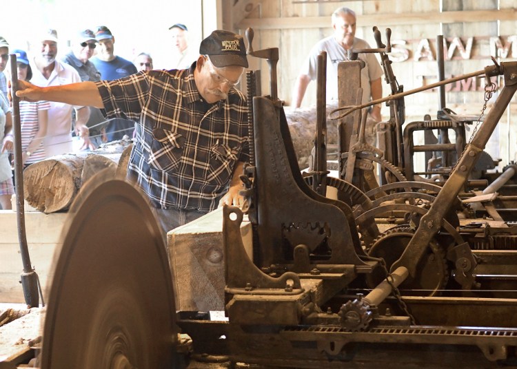 Bob Brown, left, and Jim Hawkes cut a log Sunday at the saw mill recently reassembled at the Windsor Fairgrounds.