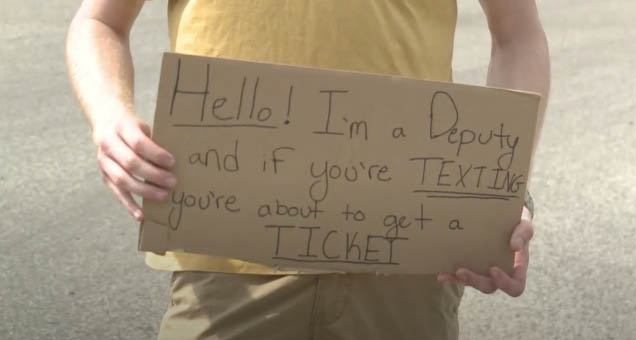 Sagadahoc County Sheriff's Deputy Zach Kinderlan holds a sign warning drivers not to text and drive.