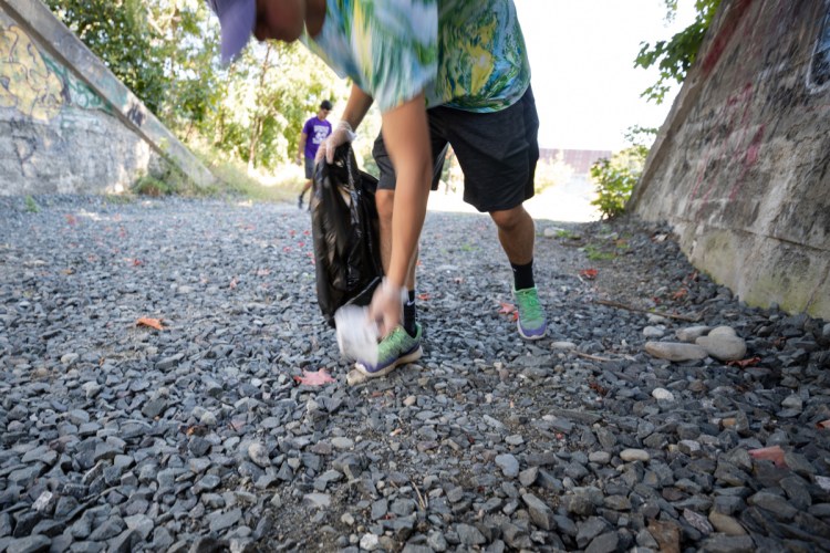 Conrad Ayers, 17, of Waterville High School's Green Team, picks up litter Saturday afternoon at the Head of Falls area in Waterville as part of a community litter cleanup event.