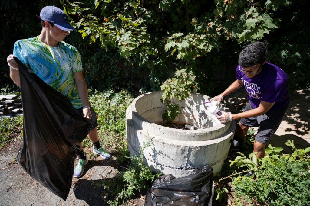 Conrad Ayers, left, 17, of Waterville, and Taylor Bielecki, 16, of Waterville, clear out a concrete fitting in the parking lot of Head of Falls in Waterville. Both are part of Waterville High School's Green Team and participated in a community litter cleanup on Saturday afternoon. Ayers and Bielecki removed at least 20 foam coffee containers from the fitting, which appeared to be serving as a garbage can. Ayers said the Green Team worked to reduce the use of styrofoam food containers in the high school.