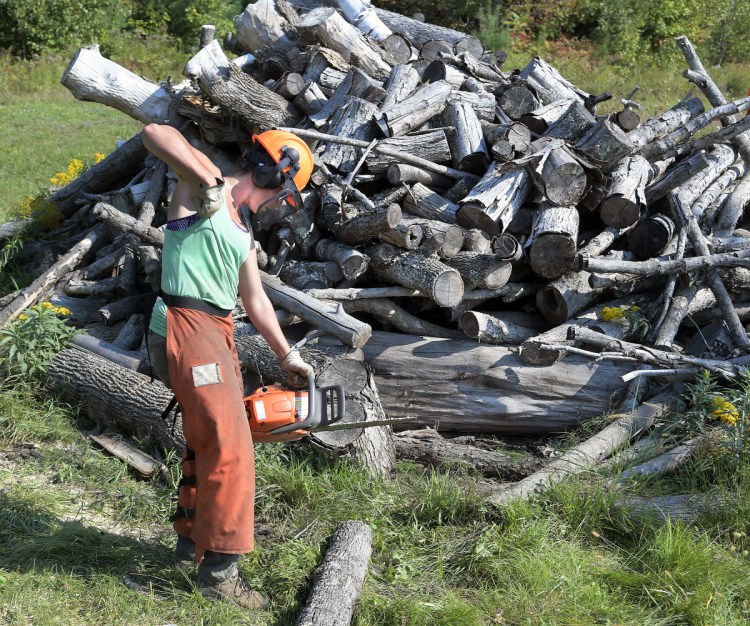 Anna Carll fires up a chainsaw Sunday while cutting wood at the Readfield transfer station. Carll, a town employee, volunteered her time with several residents of the community to split wood for residents to utilize as heat this winter.