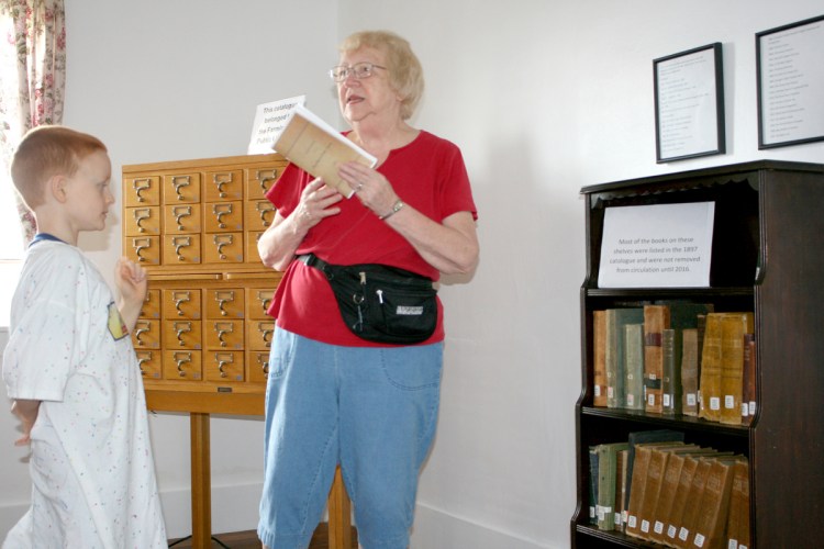 New Sharon Town Librarian Diana Oliver talks with a boy Tuesday at the Farmington Fair about how libraries began as small collections of books that were shared among townspeople. The original New Sharon Town Library and some of its original collection were moved to the fairgrounds this year.