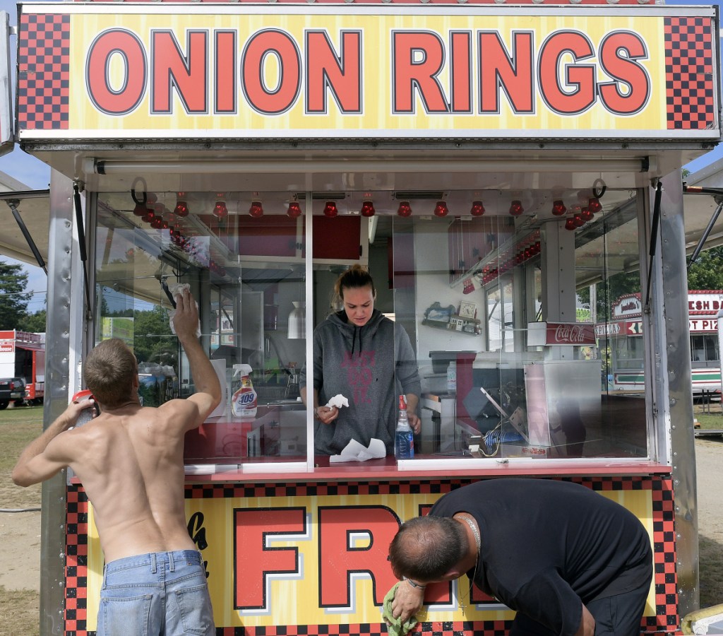 Benjamin Peaslee, left, Jeana Wilson and her husband, Edson, clean a food stand at the Litchfield Fairgrounds on Wednesday.