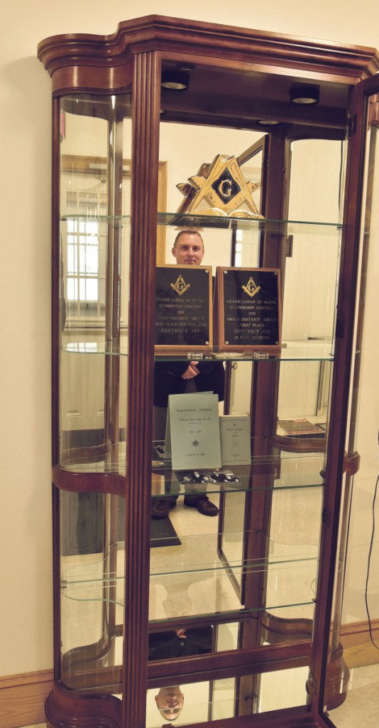 Mason Brian Nelson is reflected in a display filled with historic items of Northern Star Lodge 28 on Thursday in North Anson, The Masons plan to celebrate the lodge's bicentennial on Saturday with a barbecue, music, vendors and entertainment.