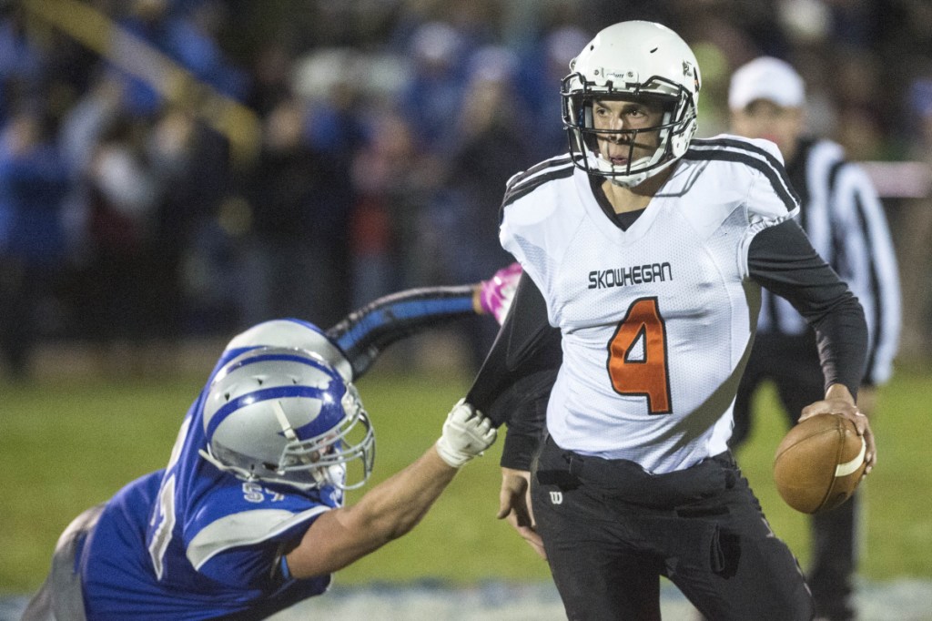 Skowhegan quarterback Marcus Christopher (4) tries to scramble away from the sack by Lawrence's Sumner Hubbard on Friday in Fairfield.