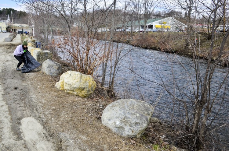Diane Twombly picks up trash in the Arcade parking lot behind Water Street on April 21 along the banks of Cobbossee Stream in downtown Gardiner. Gardiner officials are considering stricter dog rules after an incident in July where a woman was attacked by two dogs that were not under leash control in the Arcade parking lot.