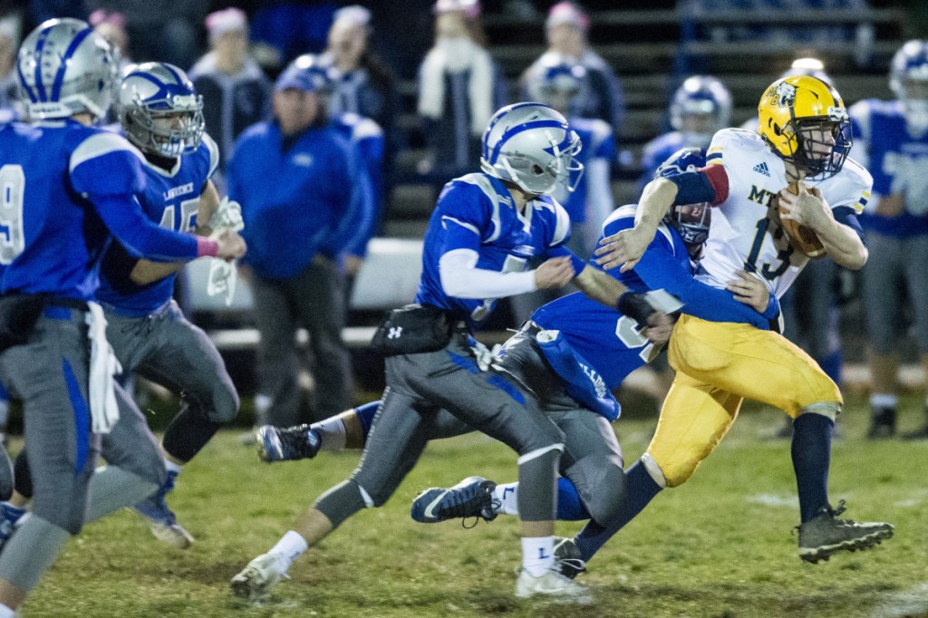 Mt. Blue's Caleb Haines (13) tries to break away from a pack of Lawrence defenders during a Pine Tree Conference Class B quarterfinal round game Friday night at Keyes Field in Fairfield.