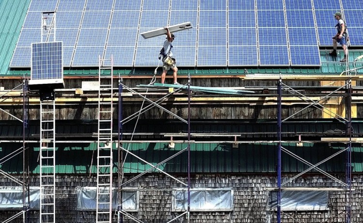 ReVision Energy workers install solar panels to a restored barn at the Maine Organic Farmers and Gardeners Association property in Waldo County in 2016. An Efficiency Maine grant helped finance the project.