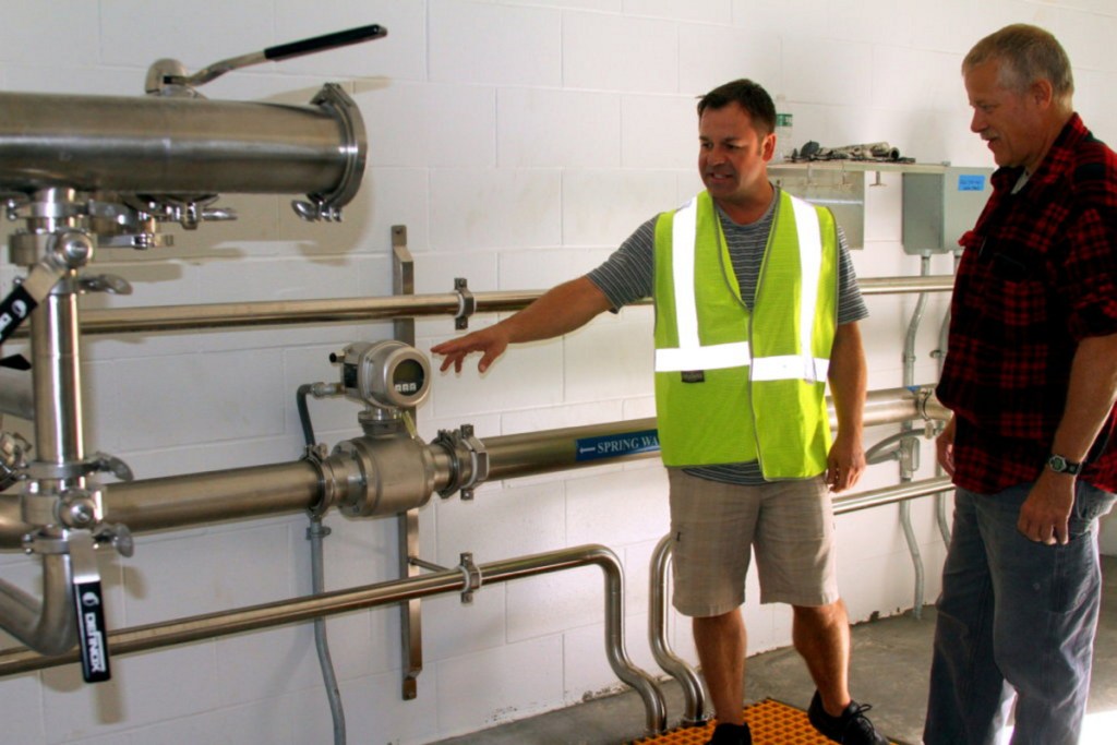 Mark Dubois, a Poland Spring hydrogeologist and the company's natural resource manager, points out a flow meter Thursday to Rumford Water Superintendent Brian Gagnon. This is one of two bore hole buildings from the Ellis spring site that will deliver water through more than 3 miles of pipeline to the loading station. Production will begin in 2019.