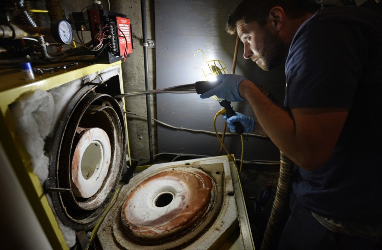 Mark Koteles of Charlie Burnham Energy and Heating Services in Freeport cleans a heating system at the North Yarmouth White Pine Community Church last week. The July 1 switch to ultra-low sulfur heating oil – many Maine homes are already burning it – is not expected to affect prices, which fluctuate with demand.