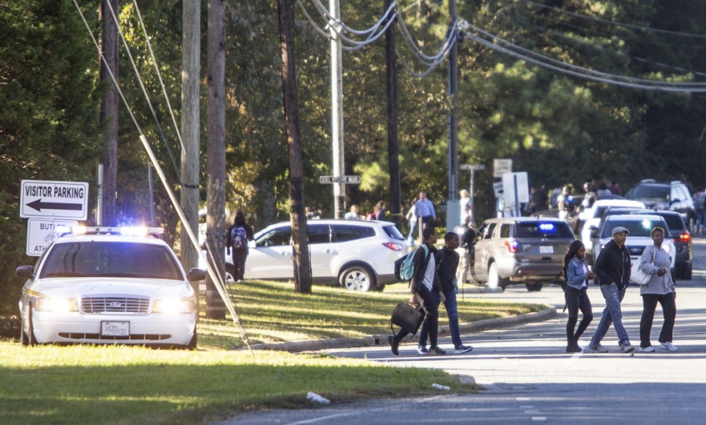 Parents walked to go pick up their kids outside Butler High School after the scene was considered safe in Matthews, N.C., Monday, Oct. 29, 2018. A student shot and killed a fellow student during a fight in a crowded school hallway Monday, officials said, prompting a lockdown and generating an atmosphere of chaos and fear as dozens of parents rushed to the school to make sure their children were safe.  (Joshua Komer/The Charlotte Observer via AP)