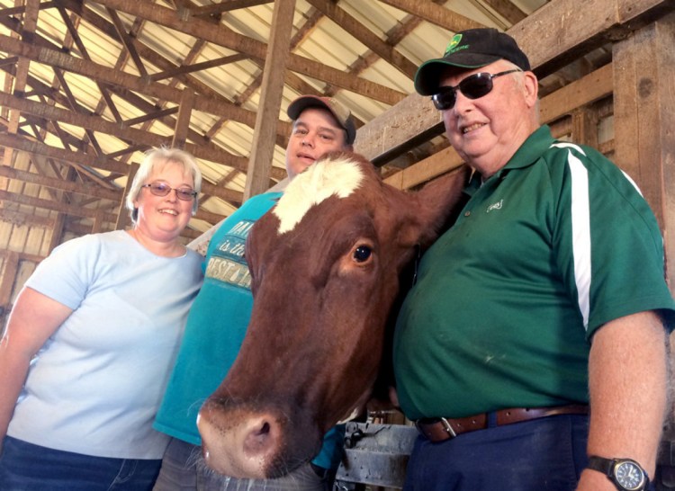 Trudy and Erik Johnson and Bussie York, Trudy's father, stand in one of the barns at Sandy River Farms in Farmington last summer. The farm cut back its milking herd in September after abruptly losing its commercial milk contract, one of about eight farms dropped at the same time. They're hoping a farm market and buy-local push can sustain the farm.