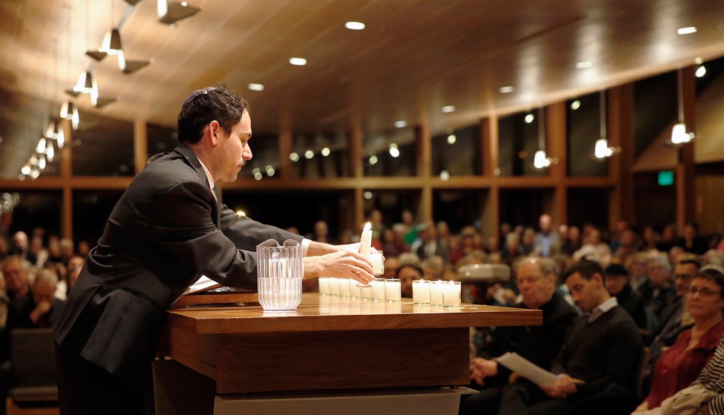 Rabbi Jared Saks lights a candle in memory of Dr. Jerry Rabinowitz, who was killed Saturday in the mass shooting at shooting at Tree of Life synagogue in Pittsburgh. Candles were lit for all 11 people who were killed.