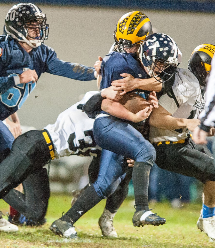 Maranacook's Joe Albert, left, assists teammates to bring down Dirigo's Dallas Berry during Friday night's Class E playoff game in Dixfield.