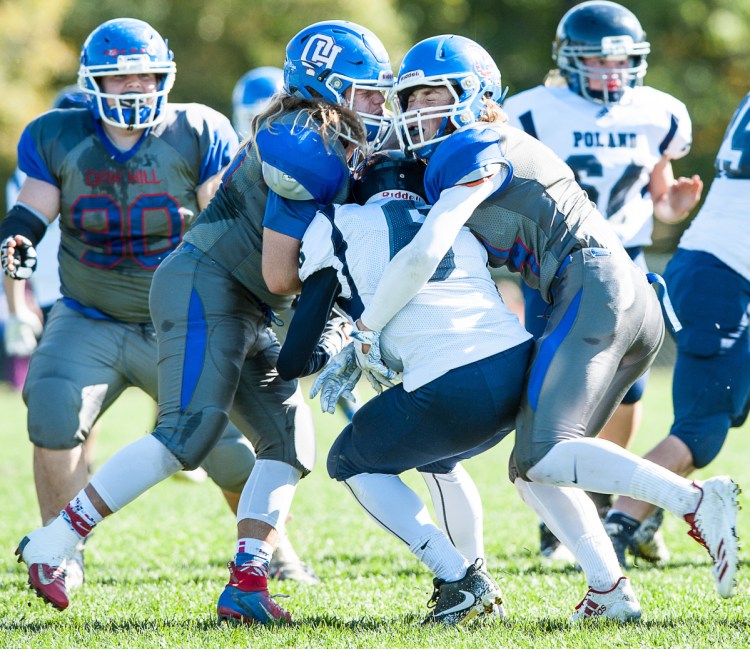 Oak Hill linebacker Ethan Richard, left, and teammate Samuel Lindsay, right, knock facemasks as they hit Poland quarterback Isaiah Hill in the backfield for a loss during the first half of a game earlier this season in Wales.