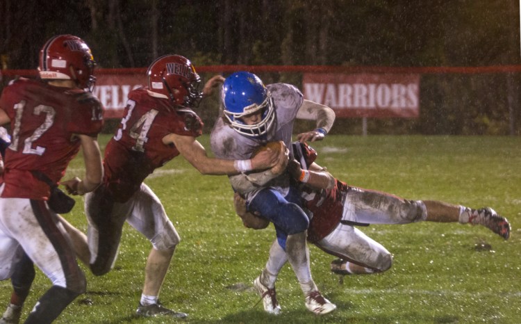 Oak Hill's Samuel Lindsay (14) is taken down by two Wells players during the first half of the Class D South football final on Friday night in Wells.