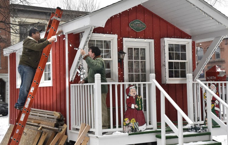 Rick Dutil, left, and Scott McAdoo string Christmas lights on Kringleville in Castonquay Square in Waterville on Monday. This Friday following the Parade of Lights in downtown Kringleville will open for the holiday season.