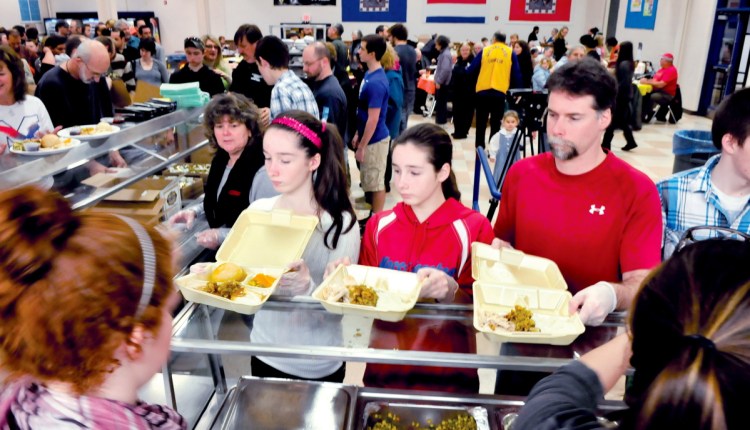 The Vigue family pitches in to serve dinners on Nov. 28, 2013, during the Messalonskee Thanksgiving Day Community Meal in Oakland. This year's meal is expected to feed about 1,300 people.