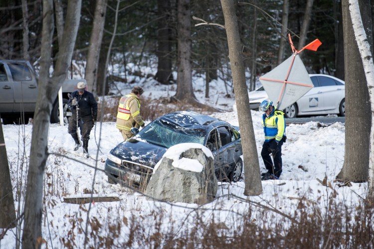 Waterville firefighter Lt. Scott Holst, of Engine 2, along with a Delta Ambulance emergency medical technician and a tow truck driver from Arbo's, tend to a car that went off the road Wednesday near exit 127 in the southbound lanes of Interstate 95 in Waterville.