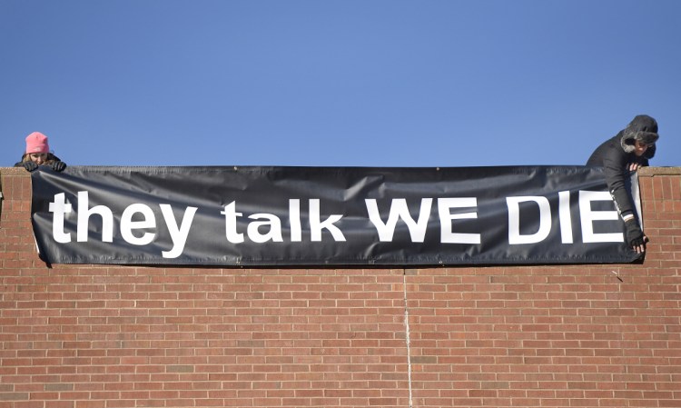 Nina Shamus and Glenn Simpson of Overdose Prevention Sites hang a banner from the Temple Street parking garage in Portland on Friday. "There's a lot of awareness that needs to be raised and lot of minds that need to be changed," said Portland OPS member Lizzy Handschy.