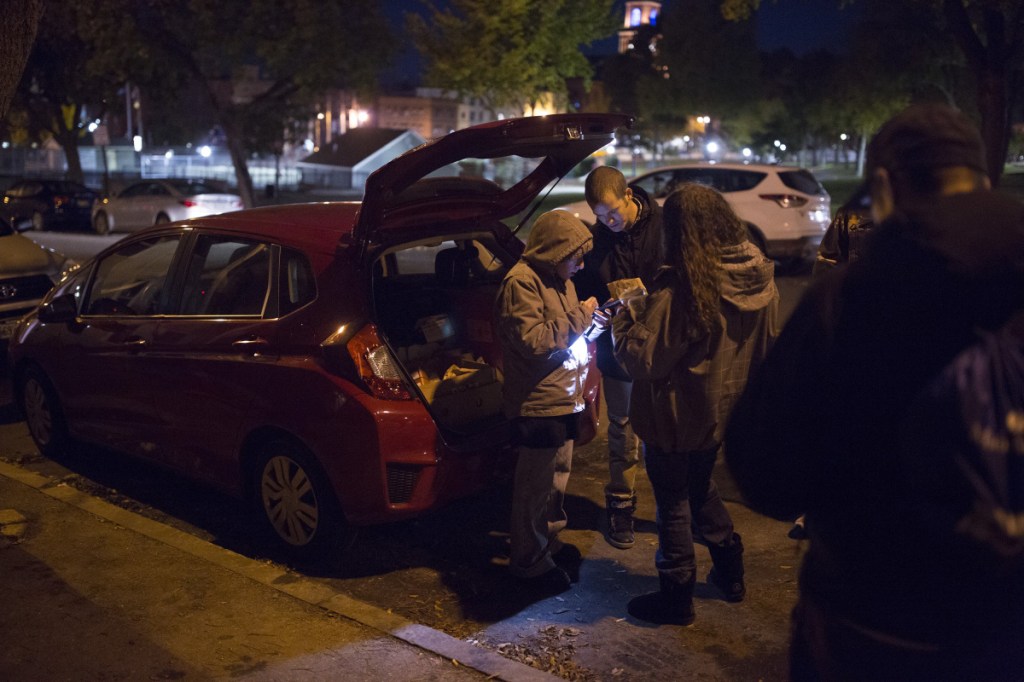 Jesse Harvey, founder of the Church of Safe Injection, center, shows a volunteer, left, how to take inventory of what they are passing out while making a kit near Kennedy Park in Lewiston in October.