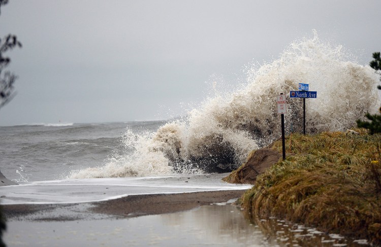 Waves crash over barriers onto North Avenue at Camp Ellis in Saco on Nov. 27.