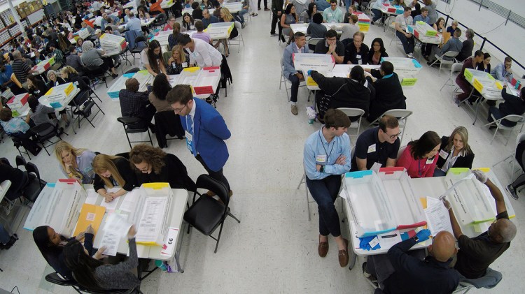 Workers at the Broward County Supervisor of Elections office, foreground, show Republican Democrat observers ballots during a hand recount, Friday, Nov. 16, 2018, in Lauderhill, Fla. 