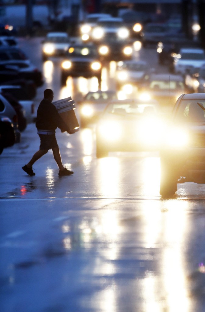 A delivery man dodges raindrops in 2015 as he crosses Main Street in downtown Waterville. The city of Waterville is to receive a $7.3 million grant to fund new traffic patterns and other infrastructure improvements downtown.