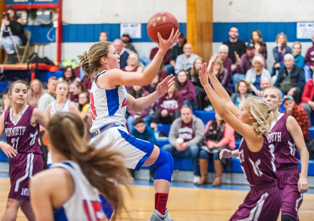 Oak Hill's Julia Noel found a lane and drives for the basket but Monmouth's Audrey Fletcher stood her ground and drew a charge against Noel during the first half of Saturday's girls basketball game in Wales.