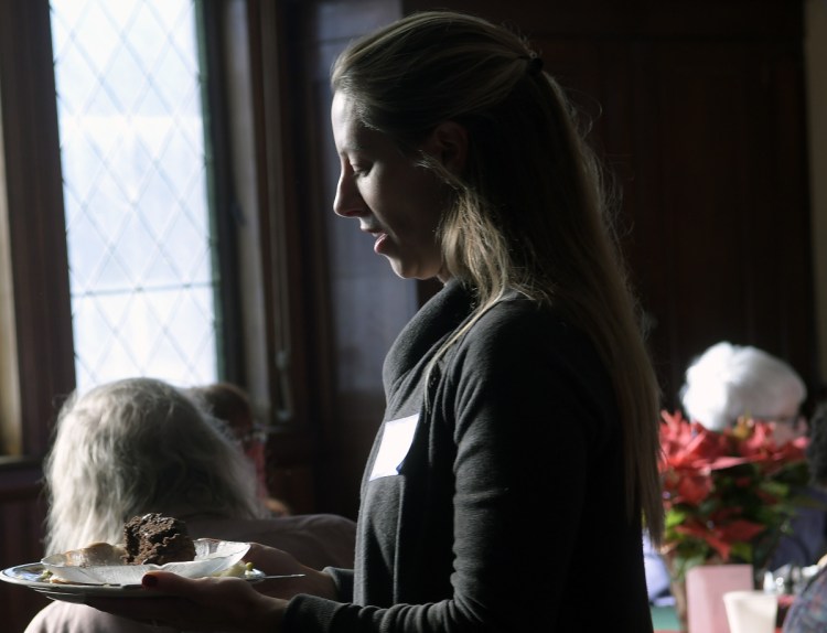 Sarah Moody collects a dish Tuesday from a guest during the Christmas dinner served at the Old South Congregational Church in Augusta. A native of Winthrop, Moody travels the globe most of the year but volunteered with her parents and siblings to serve and bus during the free meal for the community.