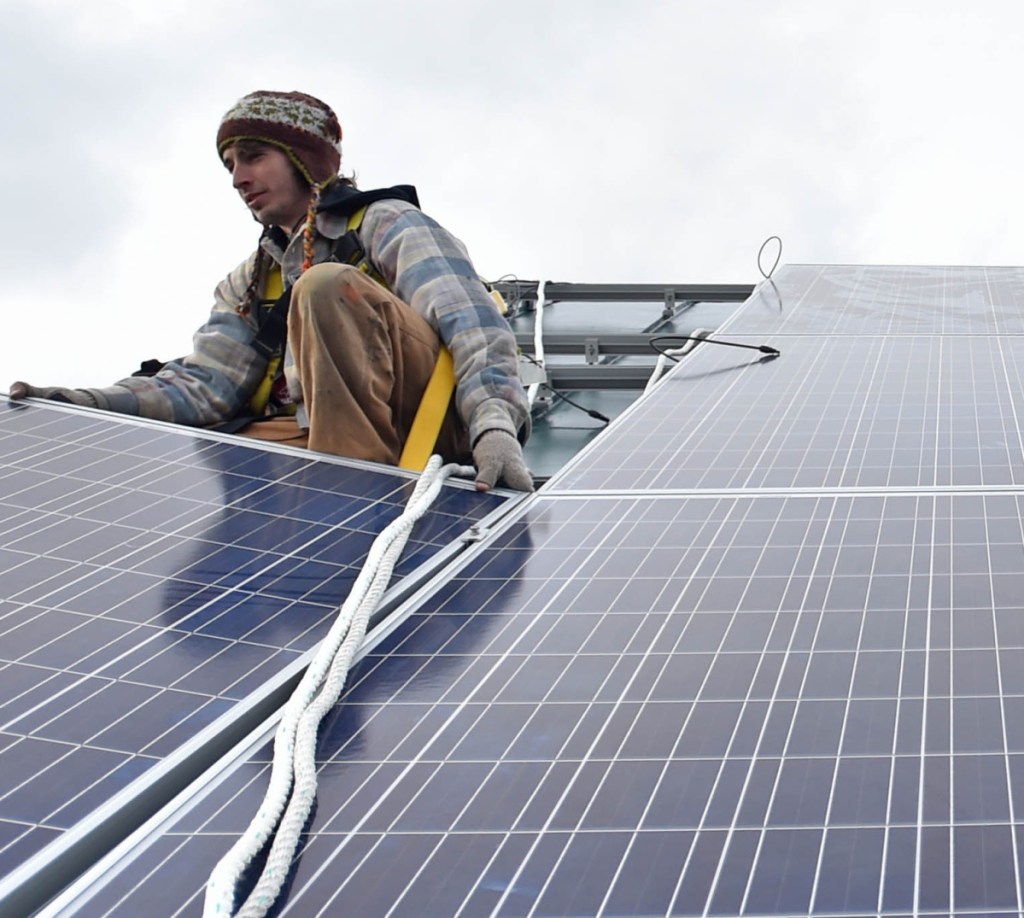 Ben Holt of InSource Renew- ables installs a solar panel on the Vassalboro Friends Meeting House in 2016.