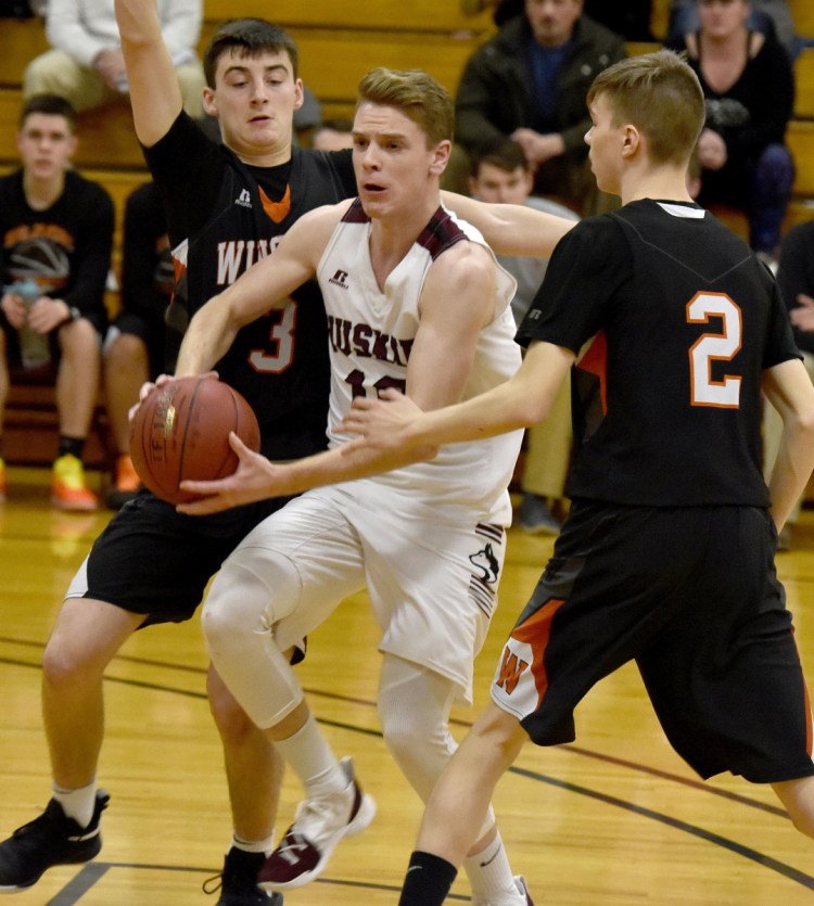 Winslow's Dillion Loiseau drives through MCI's Dominic Wilson, left, and Joe Cloutier during a game Thursday in Pittsfield.