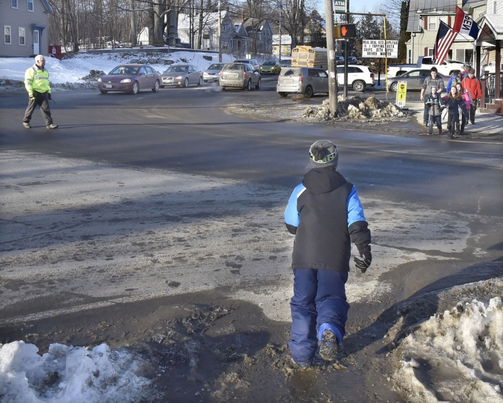 A crossing guard halts traffic for RSU 18 school children to cross at the intersection of Oak and Pleasant streets in Oakland on Tuesday. The spot is busy with traffic and is in the middle of four school buildings.