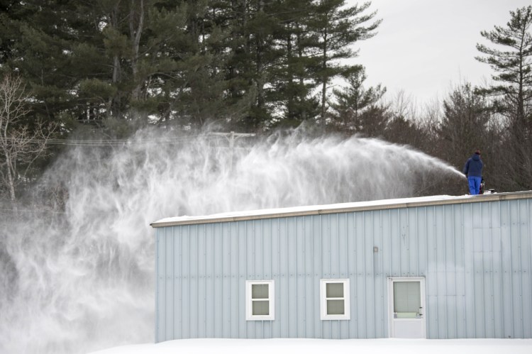 Workers remove snow Wednesday from the roof of the Maine Grain Alliance building in Skowhegan.