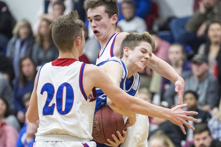 Erskine's Austin Dunn, center, draws a foul as he tries to split Messalonskee defenders Mason Violette, left, and Tucker Charles during a Kennebec Valley Athletic Conference Class A game last season in Oakland.